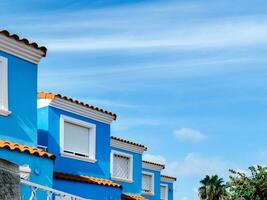 view of several identical windows of a blue townhouses against the background of the sky with light clouds photo