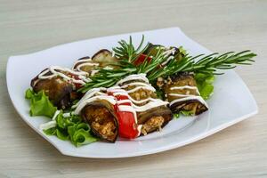 Aubergine roll on the plate and wooden background photo
