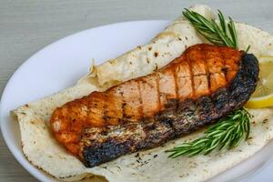 Grilled salmon on the plate and wooden background photo