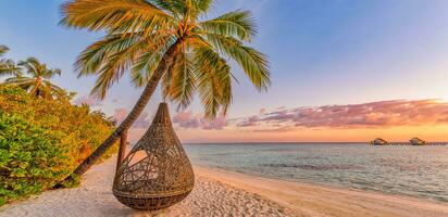 Tropical sunset beach background as summer landscape panorama with beach swing or hammock and white sand and calm sea beach banner. Perfect beach scene vacation or summer holiday concept photo