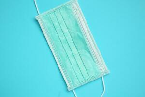 Surgical face mask on blue background protection against COVID-19 coronavirus. Healthcare and medical concept photo