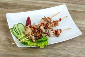 Bbq octopus on the plate and wooden background photo