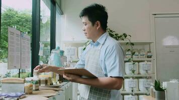 el comerciante masculino asiático verifica el stock de productos orgánicos naturales en la ventana de la tienda de recarga, supermercado sin desperdicios y sin plástico, estilos de vida sostenibles y ecológicos, tienda reutilizable. video