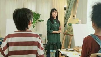en kvinna asiatisk lärare lär och demonstrerar till de barn på akryl Färg bild målning på duk i konst klassrum, kreativt inlärning med skicklighet på de elementärt skola studio utbildning.
