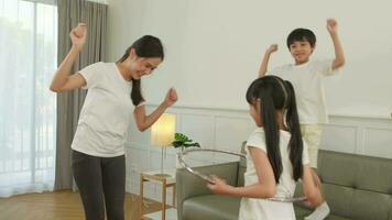 Happy wellness Asian Thai family, mother, and children are fun playing hula hoops together, fitness training and healthy exercise in white living room, domestic home lifestyle, and weekend activity. video