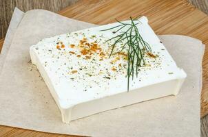 Feta cheese on wooden board and wooden background photo