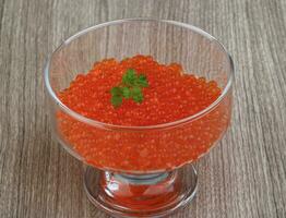 Red caviar in a bowl on wooden background photo