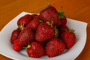 Strawberry on the plate and wooden background photo