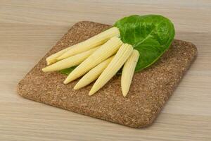 Baby corn on wooden board and wooden background photo