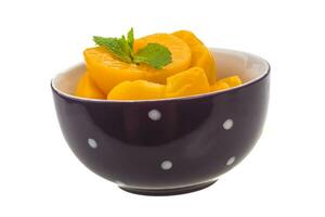 Marinated peaches in a bowl on white background photo
