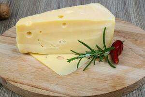 Yellow cheese on wooden board and wooden background photo