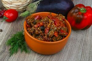 Eggplant caviar in a bowl on wooden background photo