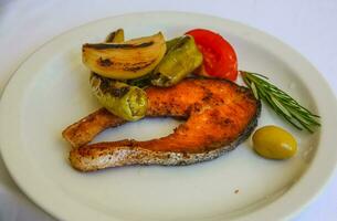 salmón a la parrilla en el plato y fondo blanco foto