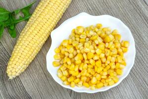 Sweet corn on the plate and wooden background photo