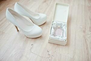 zapatos de boda blancos y perfume de rosa rosa. foto