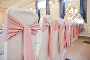 sillas con cintas rosas en la mesa de la boda en el restaurante. foto