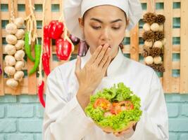 una mujer asiática con uniforme de chef está cocinando en la cocina. foto