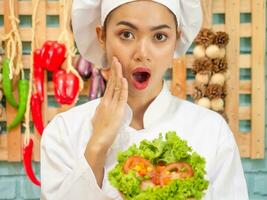 Asian woman in chef's uniform is cooking in the kitchen. photo