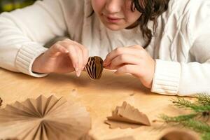 girl makes Christmas tree decorations out of paper with her own hands. step 5. step-by-step instruction photo