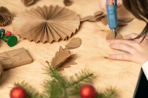 girl makes Christmas tree decorations out of paper with her own hands. step 3. step-by-step instruction photo