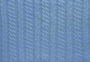 Texture of smooth knitted blue sweater with pattern. Top view, close-up. Handmade knitting wool or cotton fabric texture. Background of knitting patterns with a vertical Braid Cable. photo