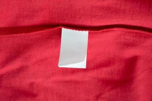 White laundry care washing instructions clothes label on red cotton shirt photo