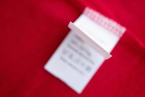 White laundry care washing instructions clothes label on red cotton shirt photo