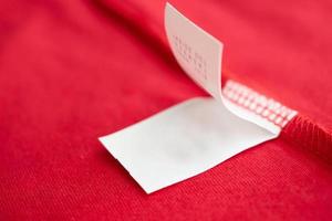 White laundry care washing instructions clothes label on red cotton shirt photo