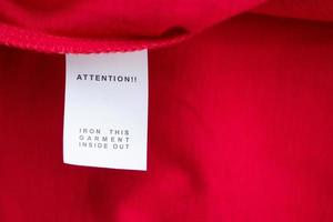 White laundry care washing instructions clothes label on red cotton shirt photo