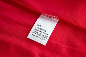 White laundry care washing instructions clothes label on red cotton shirt photo