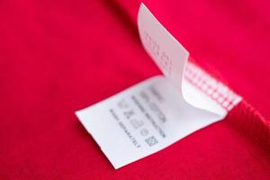 White laundry care washing instructions clothes label on red cotton shirt photo