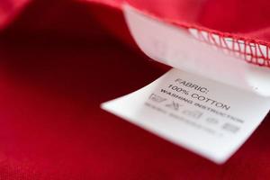 White laundry care washing instructions clothes label on red cotton shirt photo