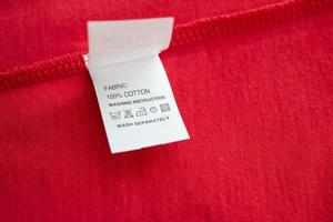 White laundry care washing instructions clothes label on red cotton shirt photo