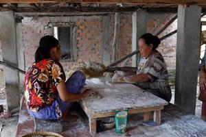 ogan ilir, indonesia - 27 de octubre de 2021, dos mujeres trabajan y hablan entre sí hacen comida tradicional foto