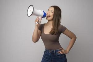 joven mujer sonriente con megáfono sobre estudio de fondo blanco. foto