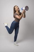 Young smiling woman holding megaphone over white background studio. photo