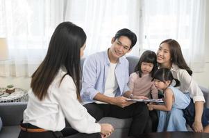 Asian family meeting with female real estate agent or insurance consultant offering promotions , Mortgage, loan, property and medical health insurance concept. photo