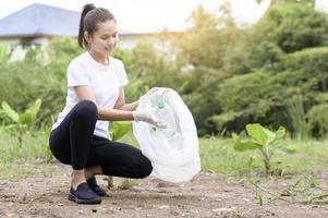 woman is collecting recycling junk on ground , ecological sustainable concept . photo