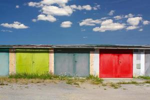 Row of old garages with colorful gates and sky with clouds. photo