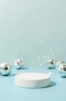 A minimalistic scene of a podium with christmas decorative balls on a light blue background photo