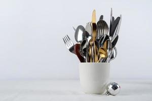 Set of cutlery of spoons, knives and forks in cup with holiday decorations on dining table, copy space