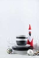 Set of black and white tableware with plates, cutlery and glasses with holiday decorations on dining table, copy space photo