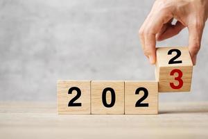hand flipping block 2022 to 2023 text on table. Resolution, strategy, plan, goal, motivation, reboot, business and New Year holiday concepts photo