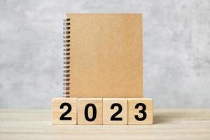 2023 feliz año nuevo con cuaderno en blanco y número de madera. concepto de cuenta regresiva, resolución, objetivos, plan, acción y misión foto