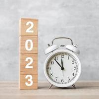 feliz año nuevo con despertador vintage y bloque 2023. concepto de navidad, nuevo comienzo, resolución, cuenta regresiva, metas, plan, acción y motivación foto