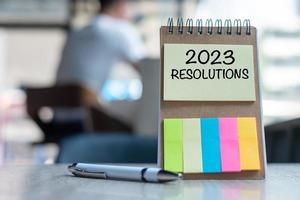 2023 Resolution word on note paper with pen on wooden table. strategy, solution, goal, business, New Year New You and happy holiday concepts photo