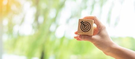 hand hold dartboard block with business goal, strategy, target, mission, action, objective, aim and success concept photo