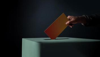 Election Concept. Person Dropping a Ballot Card into the Vote Box, Dark Cinematic Tone photo