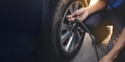 Man filling Air into the Tire. Car Driver Checking Air Pressure and Maintenance his Car by himself before Traveling photo