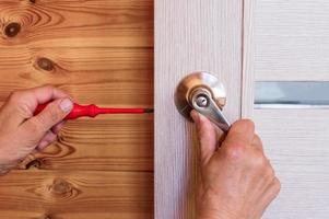 primer plano de la mano del hombre instalando la cerradura de la puerta en casa foto